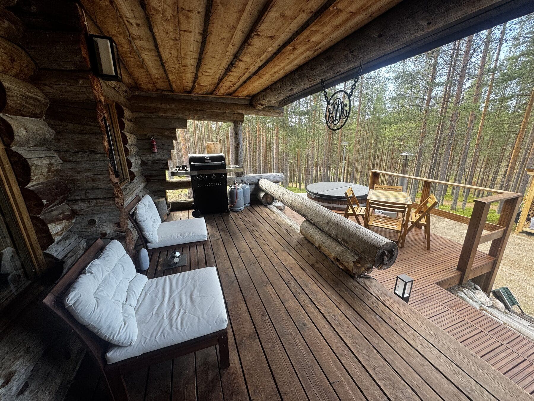 Kesäinen katettu terassi, jolla lounge-kalusteet, grilli ja palju